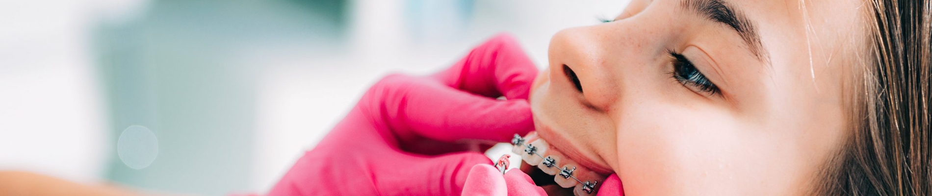 young girl having braces applied to teeth